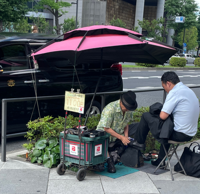 한 남성이 일본 도쿄의 도쿄역 인근에서 구두닦이를 이용하고 있다. 비용 지불은 QR결제 서비스인 ‘페이페이’를 통해서도 할 수 있다. 신중섭 기자