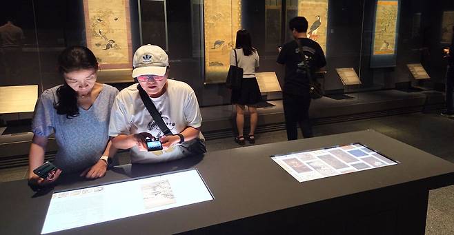 국립중앙박물관 특별전&nbsp;‘새나라 새미술’ 전시실에서 관람객들의 디지털화된 전시품 사진을 들여다 보고 있다.&nbsp;&nbsp;&nbsp;