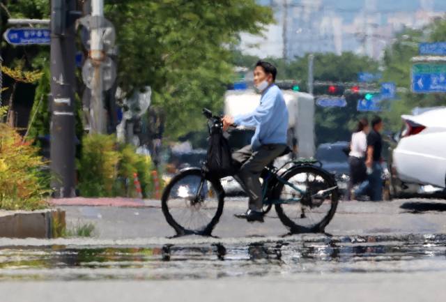 전국 대부분 지역에 폭염 특보가 발효된 3일 광주 서구 치평동에서 시민들이 강렬한 햇빛에 달구어져 아지랑이가 피어오르는 도로를 지나고 있다. 연합뉴스