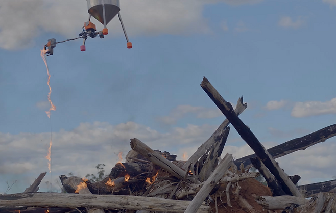 태즈드론솔루션즈의 바가르 드론에 매달린 에어리얼 드립 토치 장치에서 불똥이 떨어지고 있다.