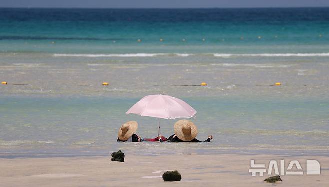 [제주=뉴시스] 우장호 기자 = 폭염의 기세가 수그러들지 않는 6일 오후 제주시 한림읍 금능해수욕장을 찾은 피서객들이 시원한 바닷물에 발을 담그며 더위를 식히고 있다. 2025.07.06. woo1223@newsis.com