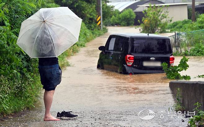 기록적인 폭우가 이어지며 수도권 지역 곳곳에 호우특보와 홍수경보가 발령된 18일 오전 화성시 황계동 한 논밭 인근 보행로에 침수차량을 탈출한 차주가 차량을 하염없이 바라보고 있다. 김경민기자