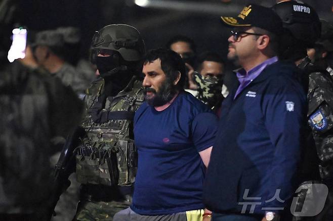 에콰도르 군·경에 의해 체포된 마약왕 아돌포 마시아스, 일명 피토(가운데)가 존 레임버그(오른쪽) 내무장관에 이끌려 호송되고 있다. 2025.6.25. RMY ⓒ AFP=뉴스1