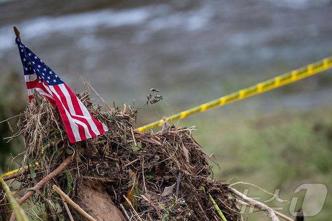 6일(현지시간) 미국 텍사스 커빌 과달루페 강변에 설치된 출입 통제선 위로 성조기가 꽂혀 있다. 텍사스를 강타한 폭우와 그에 따른 돌발 홍수로 현재까지 어린이 28명을 포함해 81명이 숨진 것으로 집계됐다. 2025.07.06. ⓒ AFP=뉴스1 ⓒ News1 윤다정 기자