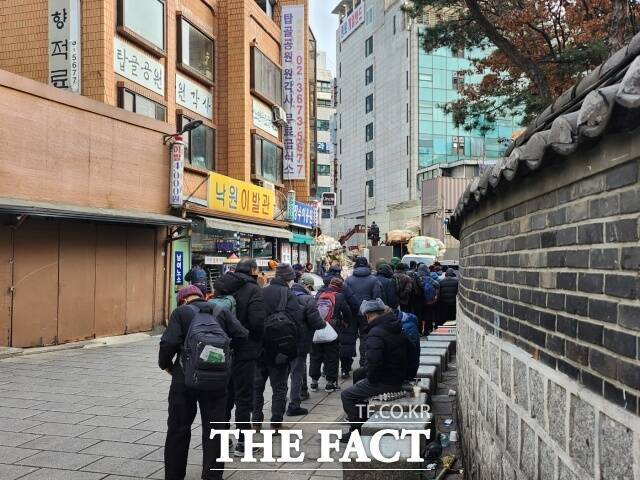 2023년 12월 19일 서울 종로구 탑골공원 인근 원각사 무료급식소 앞에서 점심을 먹기 위해 사람들이 줄을 서고 있다./사진=더팩트