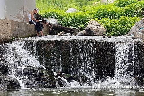 절기상 본격적인 더위가 시작된다는 소서(小暑)인 7일 경기도 광주시 남한산성 계곡에서 한 시민이 책을 읽고 있다. [경기 광주=연합뉴스]