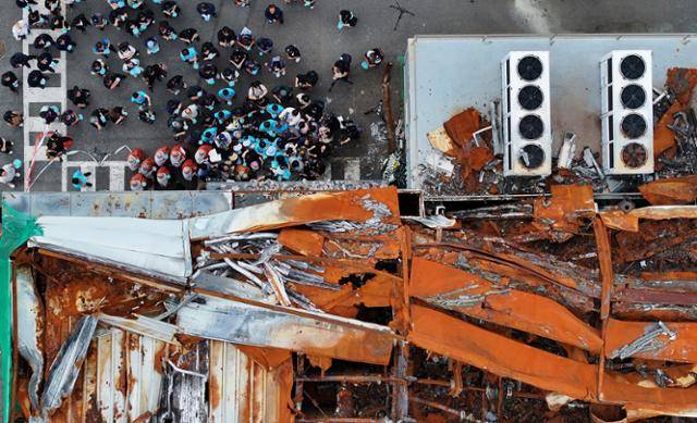 지난달 24일 경기 화성시 아리셀 화재 사고 현장에서 열린 아리셀 참사 1주기 현장 추모 위령제에서 유가족과 참석자들이 참사 현장에 헌화하고 있다. 사진은 불타버린 공장을 위에서 촬영한 것이다. 뉴스1