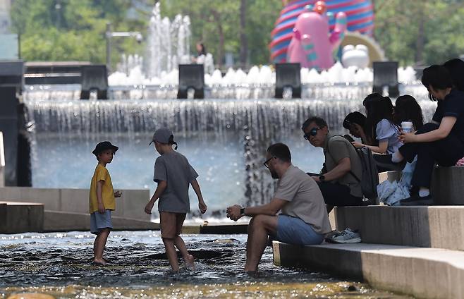 People gather in the shaded area under the Mojeon Bridge in Cheonggyecheon, an artificially restored stream running through central Seoul, Monday. (Yonhap)