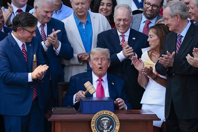 도널드 트럼프 미국 대통령(가운데)이 지난4일(현지시간)워싱턴DC 백악관에서 집권2기초대형 감세법안인 ‘하나의 크고 아름다운 법안(OneBigBeautiful Bill Act·OBBBA)’에 서명한 후 마이크 존슨 하원의장(앞줄맨왼쪽)이 선물한 의사봉으로 책상 위를 두드리면서 활짝 웃고 있다. 이의사봉은 전날 하원에서 법안이 통과될 때 존슨 의장이 사용한 것이다. [사진 = AP 연합뉴스 ]