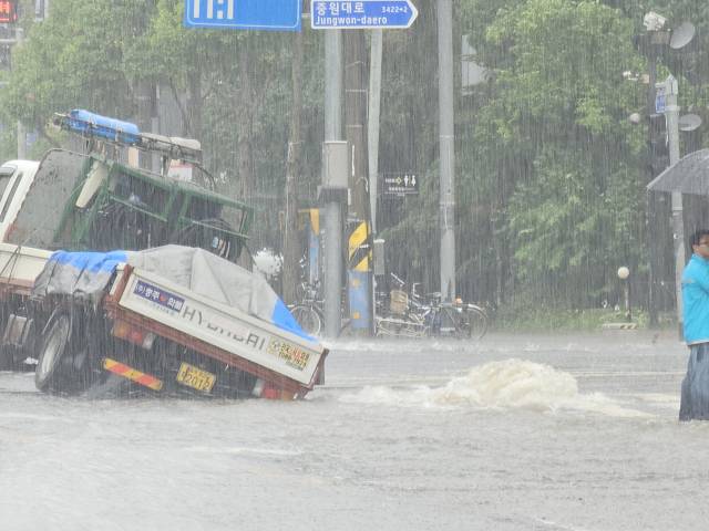 8일 오후 충주시 문화동 이마트사거리에서 발생한 씽크홀에 5톤 화물차 조수석과 적재함 쪽 바퀴가 빠져 있다. 도로가 1m 깊이로 꺼진 현장에는 상수도관 파손으로 물이 솟구친 흔적이 보이며, 운전자는 다행히 다치지 않았다.사진=김의상 기자