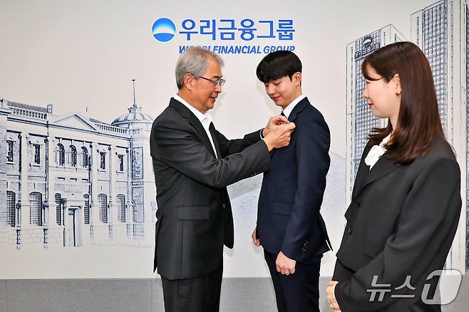 우리금융그룹 임종룡 회장이 그룹의 새 가족이 된 동양생명·ABL생명 직원에게 디지털 선도의 의미가 담긴 새로운 그룹 보조휘장을 달아주고 있다./사진제공=우리금융그룹