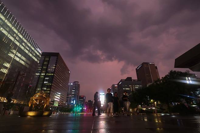 서울 최고기온이 37도까지 치솟으며 더운 날씨를 보인 8일 저녁 기습적인 폭우가 지나간 뒤 서울 종로구 광화문 광장에서 바라본 하늘이 노을로 붉게 물들어있다. 연합뉴스