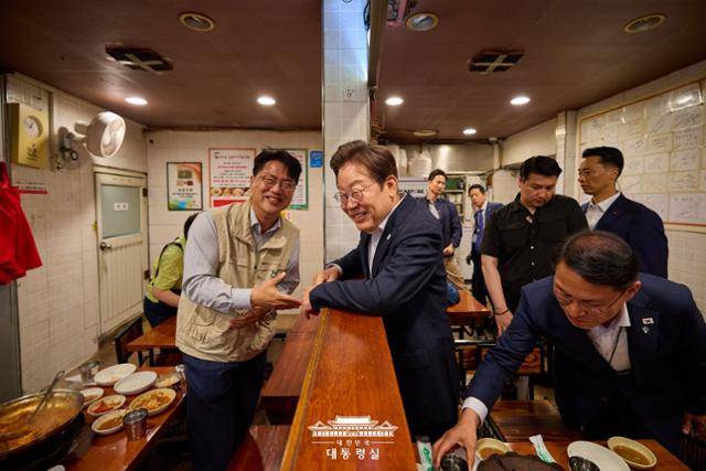 지난달 26일 서울 용산구 대통령실 인근 골목의 식당에서 점심식사를 한 이재명 대통령이 '방송 3법 개정'을 촉구하며 1인 시위를 하던 이호찬 전국언론노조 위원장을 우연히 만나 대화하고 있다. 대통령실 제공