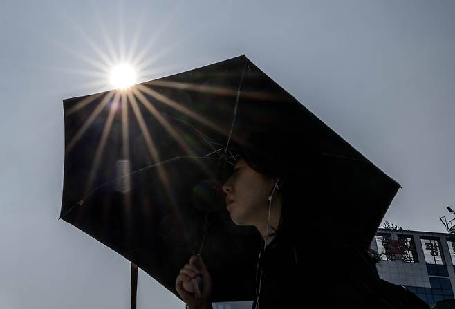 8일 오전 서울 종로구 세종대로 사거리에서 한 시민이 양산으로 뜨거운 햇살을 가리며 출근길을 서두르고 있다. 임세준 기자