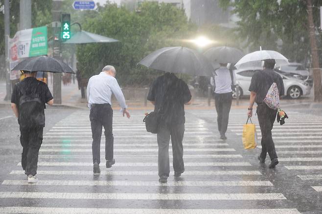 서울 서남권에 호우주의보가 발효된 8일 서울 영등포구 여의도 국회 인근에서 시민들이 우산을 쓰고 이동하고 있다. [연합]