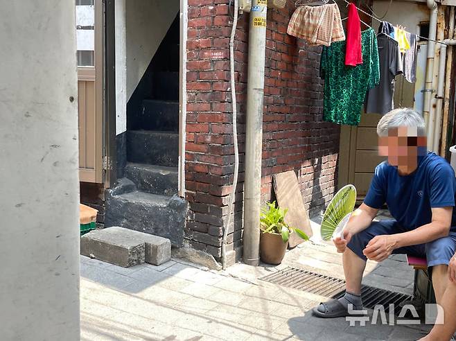 [서울=뉴시스]이채은 인턴기자 = 8일 폭염 경보가 발효 중인 서울 영등포구 쪽방촌에서 한 주민이 집안 내부의 찜통더위를 피해 골목에 나와 앉아있다. 2025.07.08