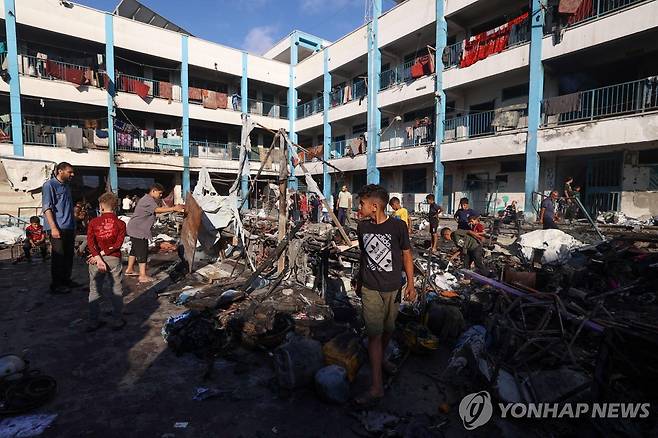 8일(현지시간) 가자지구 중부의 이스라엘 공습 현장 둘러보는 팔레스타인 피란민들 [AFP=연합뉴스]