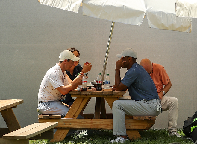 로리 매킬로이, 타이거 우즈가 골프장 파라솔에서 음식을 먹고 있다. 게티이미지