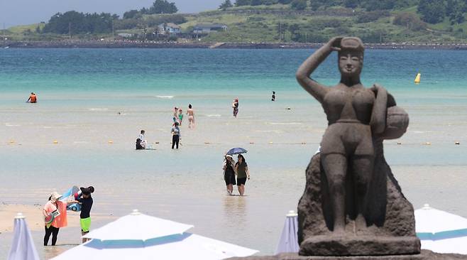 무더위가 기승을 부린 3일 오후 제주시 한림읍 금능해수욕장을 찾은 피서객들이 바닷물에 발을 담그며 더위를 식히고 있다. 뉴시스