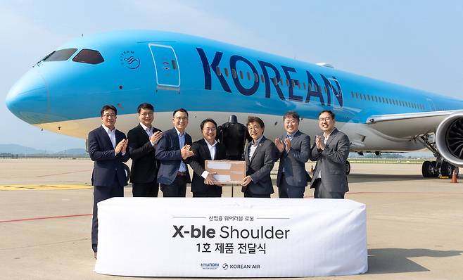 현대자동차·기아는 8일 인천시 중구 대한항공 항공기 정비고에서 산업용 착용로봇 '엑스블 숄더(X-ble Shoulder)' 1호 전달식을 진행했다. 엑스블 숄더는 무동력 토크 생성 구조로 충전 없이 작업 환경에서 근로자의 어깨 근력을 보조하는 로봇이다. 왼쪽 넷째부터 현동진 현대차·기아 로보틱스랩 상무와 정현보 대한항공 항공우주사업본부 상무.  현대차