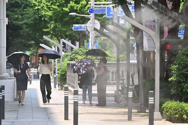 광주지역에 폭염특보가 이어지고 있는 8일 오후 광주 동구 금남로에서 시민들이 양산을 쓴 채 쿨링포그 주변을 걷고 있다. /사진=뉴시스.
