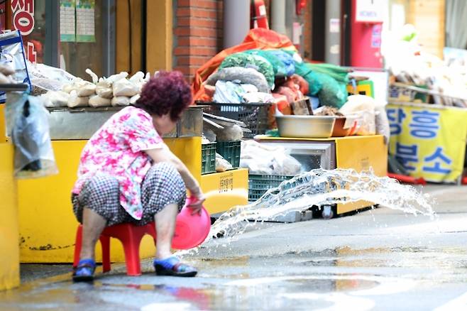 연일 폭염 특보가 이어진 9일 오전 광주 서구 양동전통시장에서 한 상인이 가게 앞 도로에 물을 뿌리고 있다. 연합뉴스