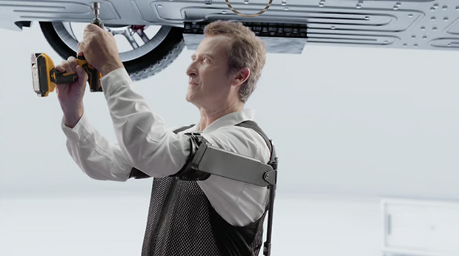 작업자가 엑스블 숄더를 착용한 채 위를 보며 차량 하부에 볼트를 결착하는 모습. 
현대자동차·기아 로보틱스랩 제공