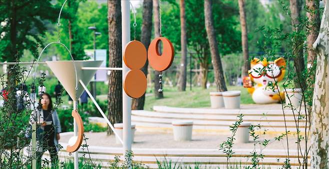 프랑스 패션기업 디올의 ‘디올 정원’.(왼쪽 사진) 밤에 조명이 켜지면 별빛 속에서 산책하는 느낌을 받을 수 있다. 아래는 국내 식품기업 농심이 조성한 ‘인위자연(人爲自然) 정원’. 너구리 캐릭터 조형물 주위에 컵라면을 형상화한 의자를 배치했다.   서울시 제공