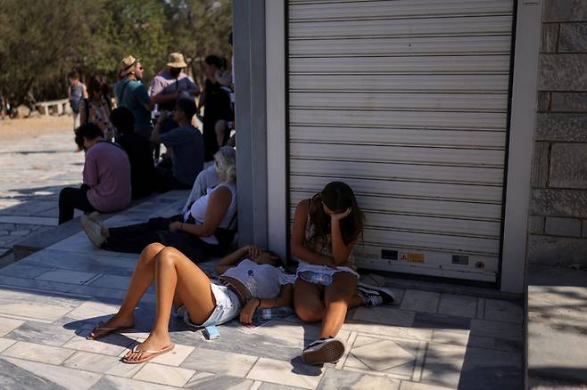 9일(현지시간) 그리스 기온이 40도까지 치솟으면서 아크로폴리스를 찾은 관광객들이 그늘에 누워있다.로이터연합뉴스