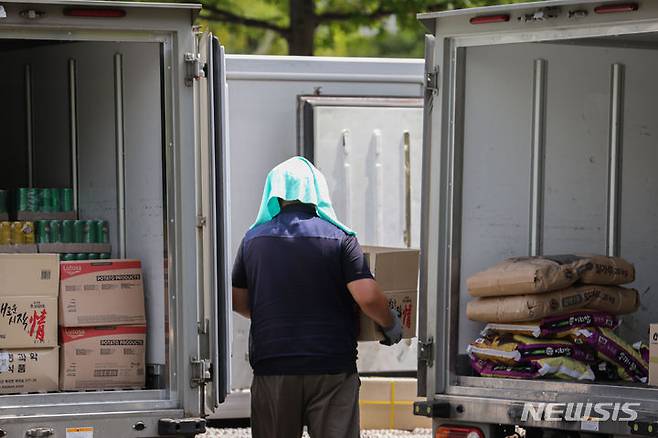 [서울=뉴시스] 권창회 기자 = 서울지역에 폭염 경보가 발령된 지난 2023년 8월4일 오후 서울 여의도 일대에서 택배기사가 햇빛을 피하기 위해 머리에 수건을 올리고 일하고 있다. 2023.08.04. kch0523@newsis.com