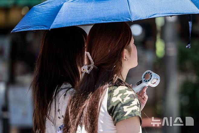 [서울=뉴시스] 정병혁 기자 = 폭염이 이어진 10일 서울 중구 을지로3가역 인근에서 양산을 쓴 여행객들이 손선풍기를 들고 이동하고 있다. 2025.07.10. jhope@newsis.com
