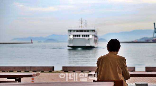 다카마쓰항의 벤치에 앉아 잔잔한 바다 위 페리를 바라보며 여행의 낭만을 만끽하는 한 여행자의 뒷모습