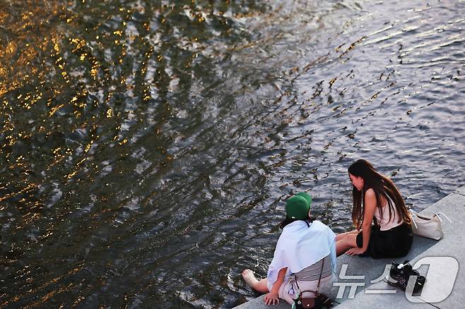 이른 폭염과 함께 열흘 넘게 열대야가 이어지고 있는 9일 저녁 서울 중구 청계천을 찾은 시민들이 더위를 식히고 있다. 2025.7.9/뉴스1 ⓒ News1 장수영 기자
