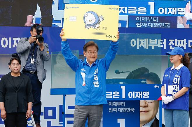 지난 5월 대통령 선거 운동 중 이재명 당시 민주당 후보가 경기도 파주시 유세에서 경기 지역 화폐인 '파주페이' 패널을 들어 보이고 있다. 이 후보는 자신의  지역 화폐 구상이 "나중에 노벨평화상을 받을 정책"이라고 했다. /뉴스1