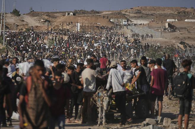 지난달 26일(현지시각) 가자 주민들이 가자 남부 칸유니스에서 가자인도주의재단(GHF) 유통센터 근처에서 인도적 지원 물품을 받고 이동하고 있다. 칸유니스/AP 연합뉴스