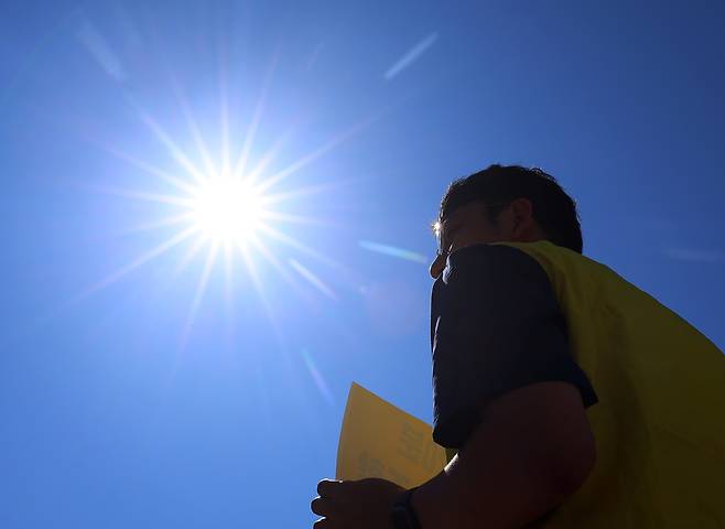 11일 서울 종로구 정부서울청사 앞에서 정부 규제개혁위원회(규개위)의 폭염 규칙 통과 촉구 기자회견을 하는 민주노총 조합원 위로 뙤약볕이 내리쬐고 있다.  연합뉴스