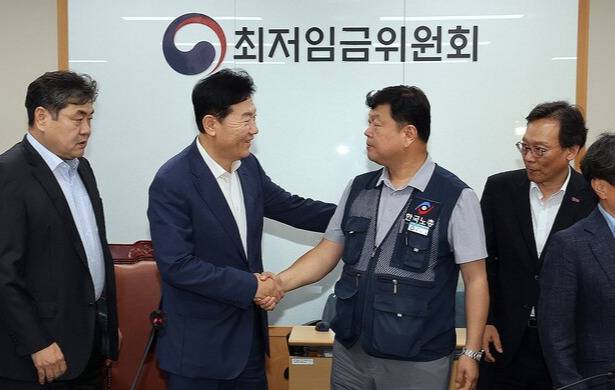 최저임금위원회 사용자위원 운영위원인 류기정 한국경영자총협회 전무(왼쪽)와 근로자위원 운영위원인 류기섭 한국노총 사무총장이 10일 정부세종청사에서 열린 제12차 전원회의에서 내년 최저임금을 시간당 1만320원으로 17년 만에 합의로 결정한 뒤 악수하고 있다. 연합뉴스