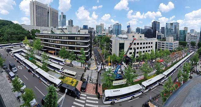 윤석열의 구속영장 실질심사가 열린 2025년 7월9일 오후 서울중앙지법 앞 삼거리가 경찰 버스와 바리케이드로 통제된 가운데 지지자들이 들머리에 모여 영장 기각 등을 외치며 집회하고 있다. 윤석열 지지자들의 집회는 전과 견주면 규모가 확연히 줄어들었다.