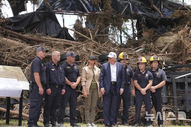 [커빌(텍사스주)=AP/뉴시스]도널드 트럼프 미국 대통령이 멜라니아 여사와 11일(현지 시간) 미 텍사스주 커빌의 홍수 피해 지역을 방문해 수색대원 등과 기념촬영을 하고 있다. 2025.07.12.