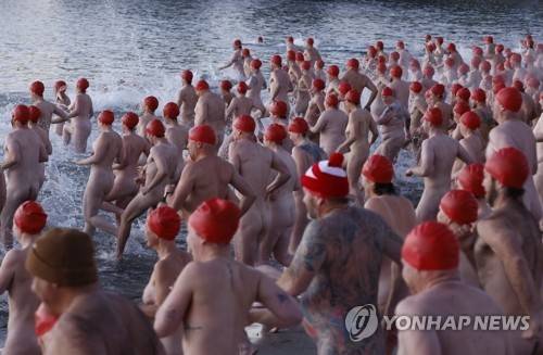 호주 겨울바다 수영축제에 참여한 시민들 호주 태즈메이니아주 호바트 샌디 베이의 롱비치에서 열린 '다크 모토 페스티벌'(Dark Mofo Festival)에서 수영모만 쓴 시민들이 바다로 뛰어들고 있다. [EPA 연합뉴스 자료사진. 재판매 및 DB 금지]