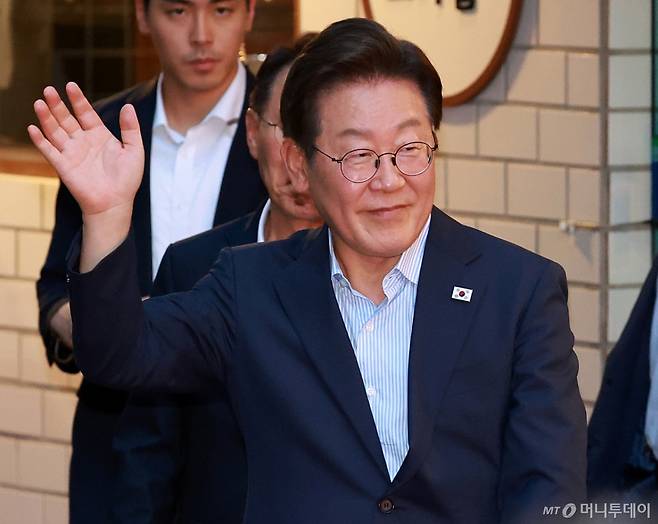 [서울=뉴시스] 이영환 기자 = 이재명 대통령이 11일 서울 종로구 광화문의 한 식당에서 식사를 마친 후 시민들에게 손인사를 하고 있다.   이 대통령은 SNS에 식사 계획을 알리며 "이처럼 어려운 시기에 21일부터 시행되는 민생회복 소비쿠폰 정책이 내수 진작과 지역 경제 활성화에 활력을 불어넣길 기대한다"고 밝혔다. 2025.07.11. 20hwan@newsis.com /사진=이영환