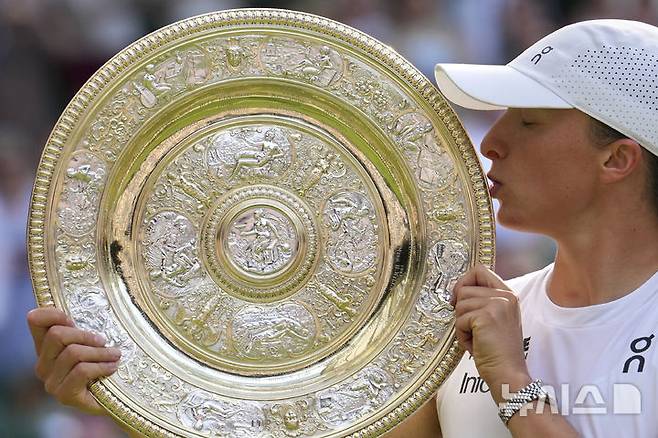 [런던=AP/뉴시스] 이가 시비옹테크(4위·폴란드)가 12일(현지 시간) 영국 런던 올잉글랜드 클럽에서 열린 2025 윔블던 테니스 대회 여자 단식 정상에 올라 트로피를 들고 입 맞추고 있다. 프랑스오픈 4회, US오픈 1회 우승 경험이 있는 시비옹테크는 결승에서 어맨다 아니시모바(12위·미국)를 2-0(6-0 6-0)으로 완파하고 첫 윔블던 우승컵을 들어 올렸다. 2025.07.13.