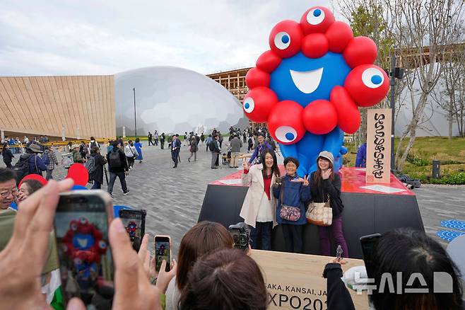 [오사카=AP/뉴시스] 오사카·간사이 엑스포 공식 개막일인 13일 박람회장을 찾은 방문객들이 공식 마스코트 '먀쿠먀쿠' 앞에서 기념 촬영을 하고 있다. 12일 개회식을 마친 이번 엑스포는 '생명이 빛나는 미래 사회의 디자인'을 주제로 오는 10월 13일까지 6개월간 열린다. 2025.04.13.