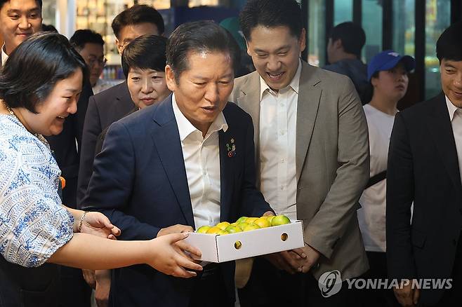 제주 감귤 구매하는 정청래 (제주=연합뉴스) 고성식 기자 = 더불어민주당 당 대표 후보인 정청래 의원이 13일 제주시 동문재래시장을 찾은 가운데 상인이 건넨 감귤을 맛본 뒤 감귤을 사고 있다. 2025.7.13 koss@yna.co.kr