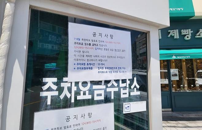 14일 찾은 울산 동구 대학길노상공영주차장. 한 주차요금수납소에 '폭염특보로 낮 12시~오후 3시 주차 요금 징수를 금지한다'는 공지문이 붙어 있다.