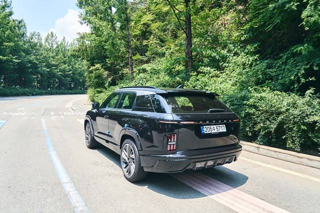 주행 중인 액티언 하이브리드의 후면. 좌우로 길게 뻗은 수평형 테일램프와 핀테일 스포일러가 조화를 이루며, 도로 위에서 안정감 있는 비율과 시각적 존재감을 강조한다. /KGM