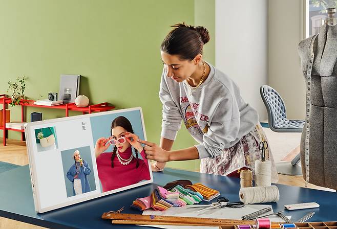 모델이 LG 스탠바이미 2의 화면부를 분리해 테이블 위에 세워두고 터치를 통해 회의 자료를 넘기며 기능 시연을 하고 있다.