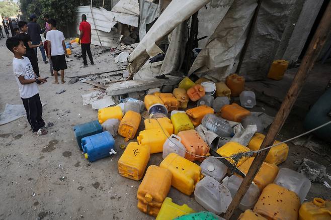 13일 가자지구 중부 누세이라트의 물 배급소에서 이스라엘군의 공습으로 어린이들이 숨진 현장을 한 어린이가 보고 있다. 로이터연합뉴스