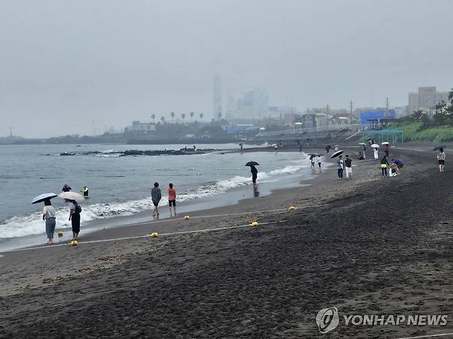 비 내리는 제주 (제주=연합뉴스) 고성식 기자 = 13일 비가 내리는 제주시 삼양해수욕장 해변에서 도민과 관광객들이 우산을 쓰고 산책하고 있다. 2025.7.13 koss@yna.co.kr