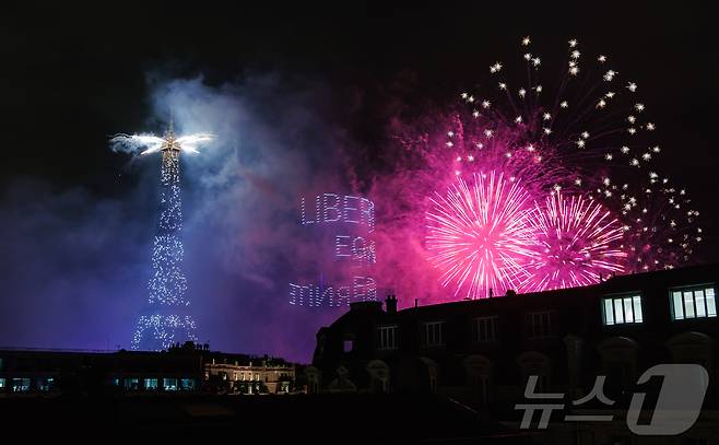 14일(현지시간) 프랑스 혁명 기념일(바스티유 데이)을 기념하기 위해 에펠탑에 펼쳐진 불꽃놀이 쇼에서 1천100대의 드론이 프랑스의 국가 모토인 ‘자유・평등・박애’(Liberté ・ Égalité ・ Fraternité)를 파리 상공에 새기며 불꽃과 함께 빛의 향연을 펼치고 있다. 2024.7.15/뉴스1 ⓒ News1 이준성 기자
